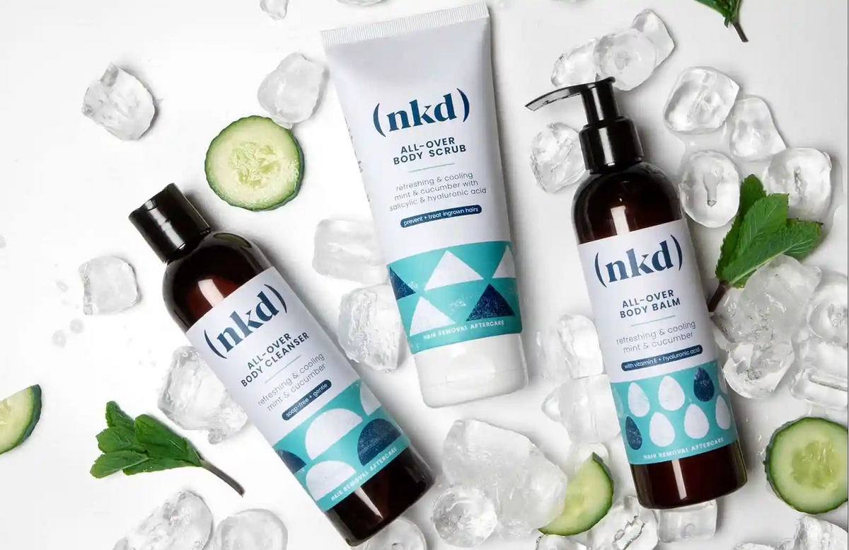 (nkd) Anti-Ingrown Hair All-Over Body Scrub and All-Over Body Balm displayed with ice and mint leaves